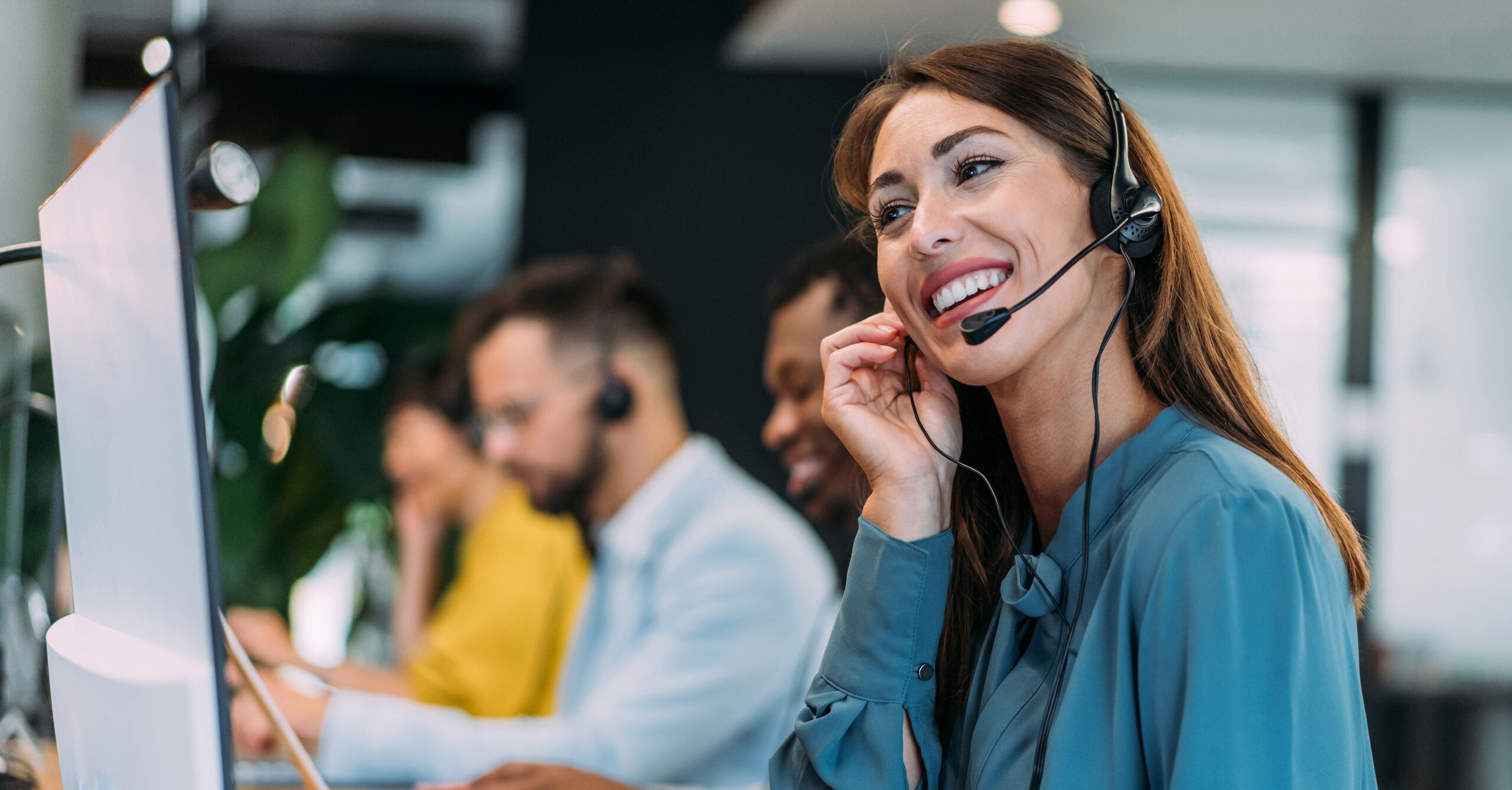 Stock image of a woman at a computer talking on her headset